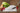 Fotografía cuchillo Roking Santoku 180 mm serie Ópera sobre una tabla de corte de mármol con rábanos, cebollas una lechuga y aceite y vinagre